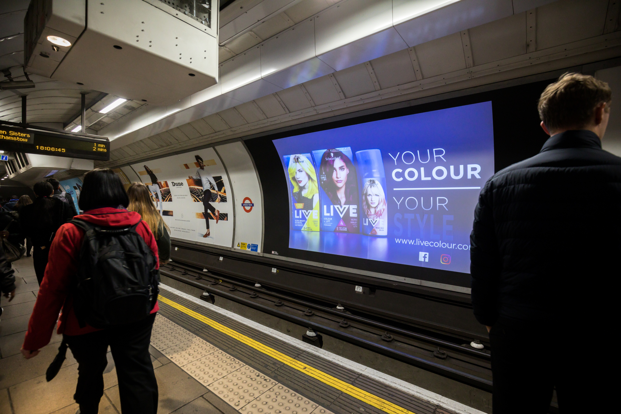 A picture of a London underground platform, showing the DX3 large digital screen across the platform